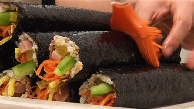 She brushes the rolled kimbap with homemade perilla oil for extra flavor. It also gives them a glossy look.