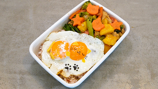 She places two fried eggs on a bed of brown rice and adds pieces of nori and cheese to make a cute kitty cat. She manages to transform imperfect produce into a delightful bento. 