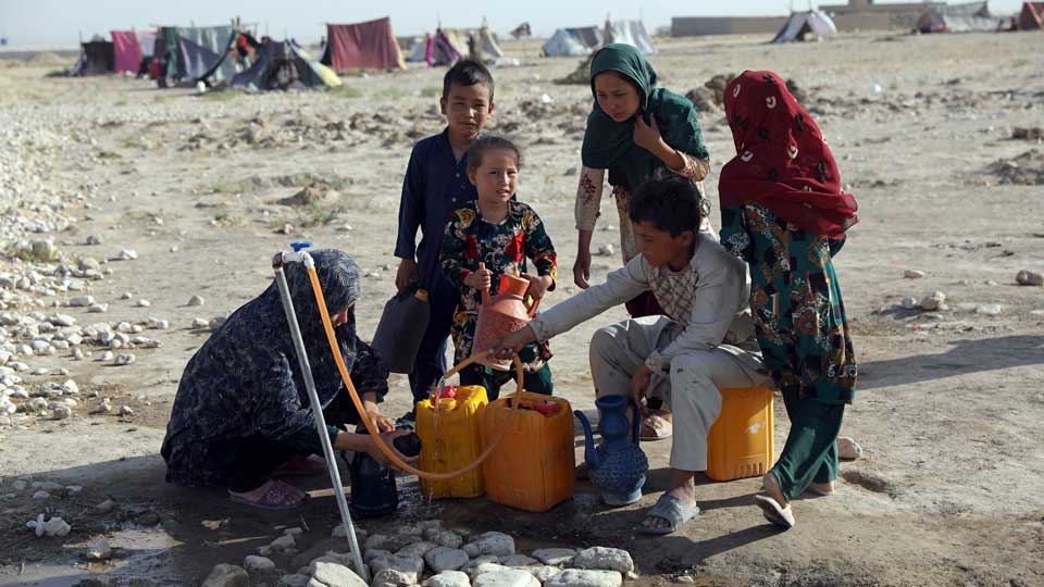 Children wait to fetch drinking water from a tanker in Kabul