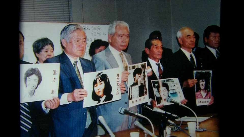 Picture of family members of people abducted by North Korea showing photos of abductees, urging the Japanese government to pressure North Korea for their return.