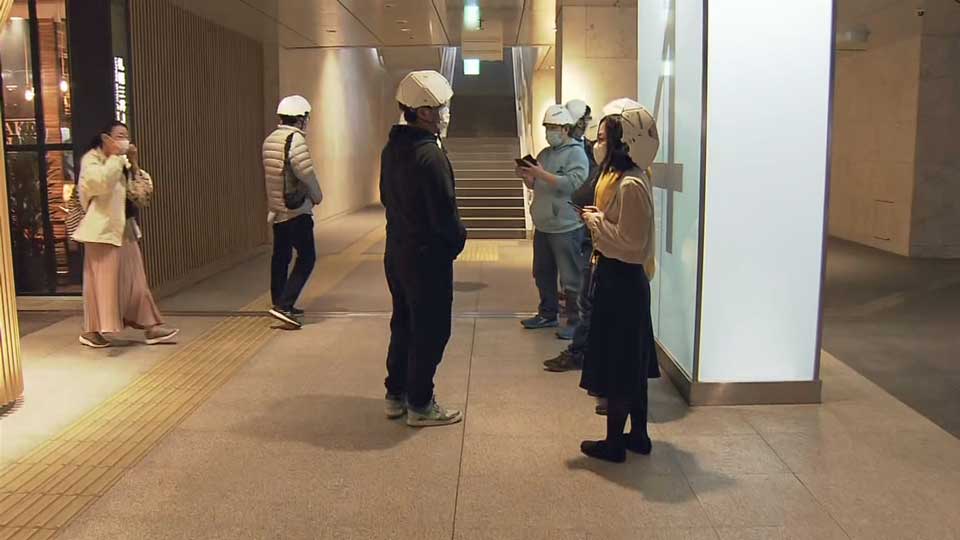 People in Sapporo taking refuge with safety helmets